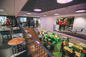 People work and spend time in the colorful Werstas Paratiisi space, which features a staircase, green work areas, and a relaxed, communal atmosphere.