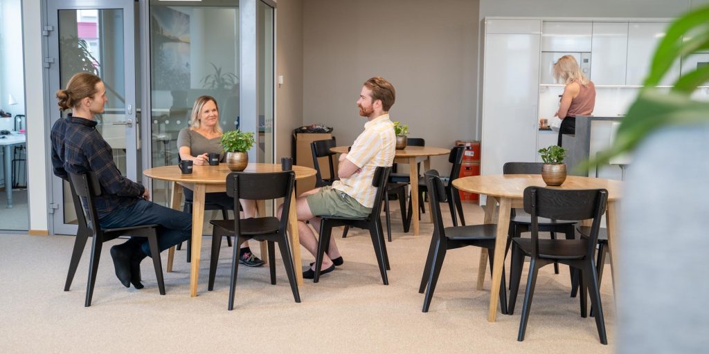 Sisätila, jossa ihmiset istuvat pöytien ääressä keskustelemassa.