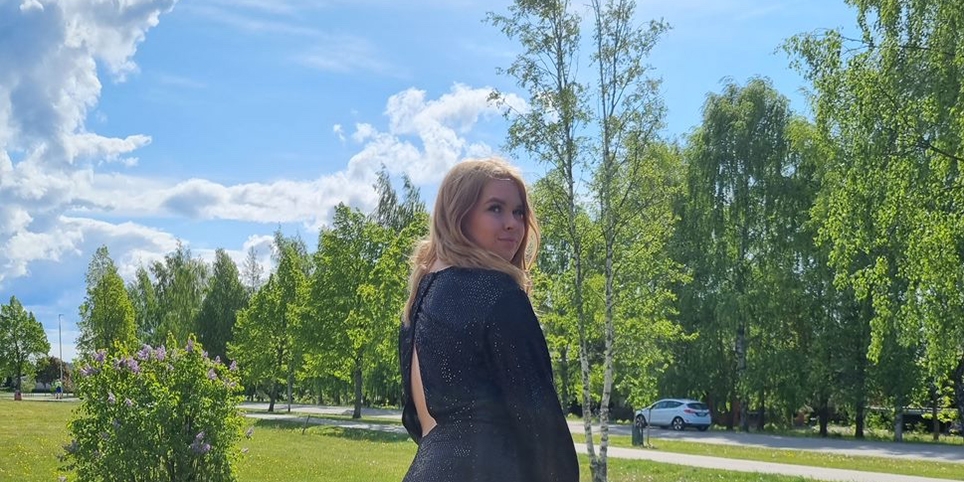 Henkilö puistomaisessa ympäristössä, taustalla puita ja kulkuväylä.